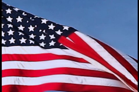 USA flag flying on the wind on blue sky background, closeup view 