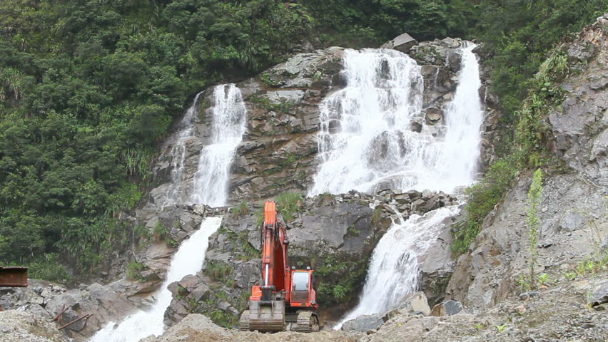 Beautiful waterfall threatened by a bulldozer in Ecuadorian Andes mountains