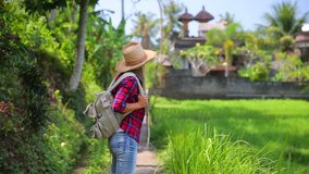 Beautiful girl traveling with backpack, slow motion, wearing straw hat, standing and looking around, enjoying beautiful nature of Asia. Full HD Video 1920x1080
