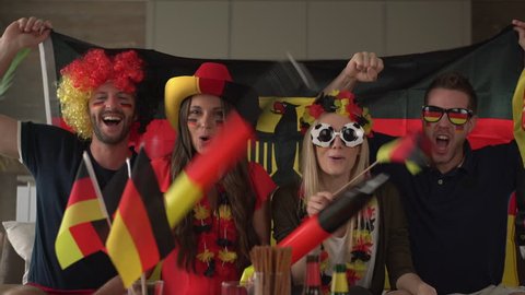 4k footage, very happy soccer fans with german flag, hat and wig cheering for Germany at home
