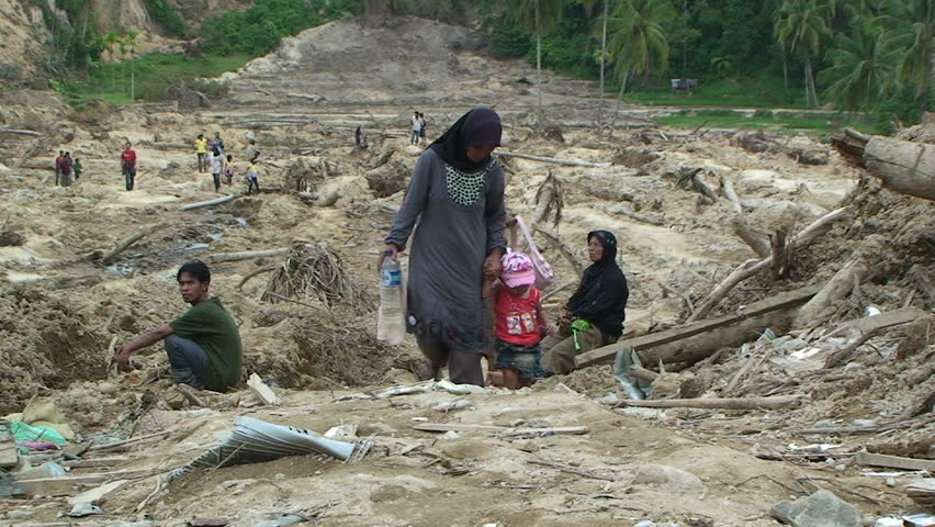PADANG, INDONESIA - CIRCA OCTOBER 2009: Survivors stand on remains of village