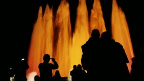 recognizable silhouettes of people in singing fountain in Barcelona. People watching the show, photographed fountain