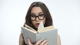 Beautiful young brunette girl in nerd glasses reading a book