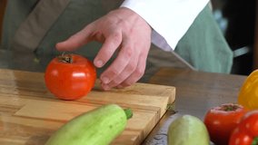 Professional chef cook is slicing tomatoes on the wooden table
