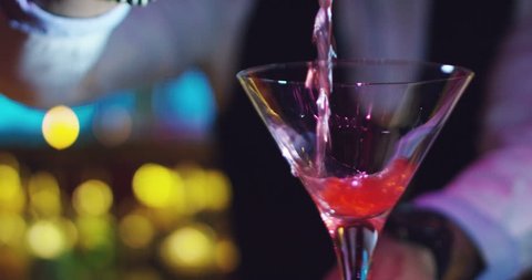 A young expert barman prepares a cocktail in a nightclub with a lot of experience and serves fresh and sweet taste.