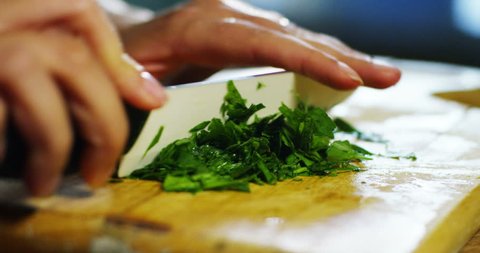 hand of an expert chef cuts the parsley, a spice that vine used to give added flavor and extra flavor to the dish. concept of freshness and fresh parsley and healthy food.