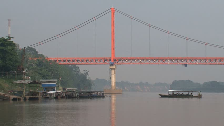 A boat pulls into dock underneath red bridge in Peru