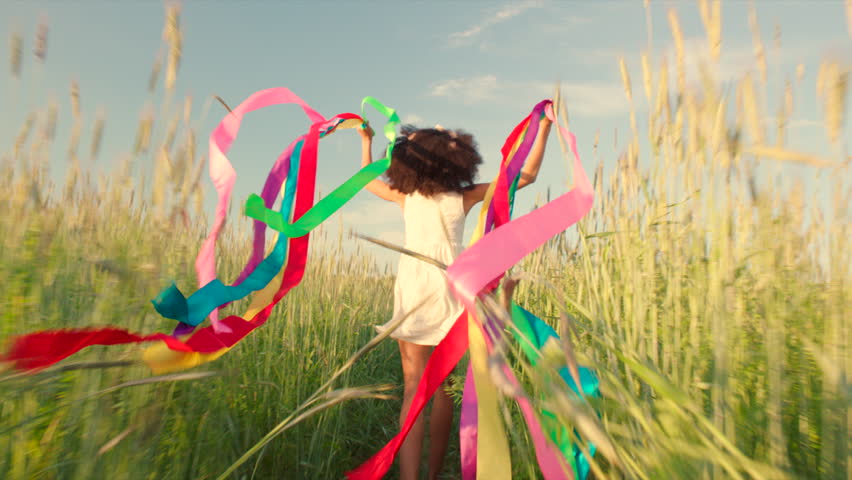 Young girl running with colored ribbons in her hands through the wheat field Royalty-Free Stock Footage #17777131