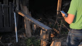 Young man making video call at sunset. A man sits at the sawmill