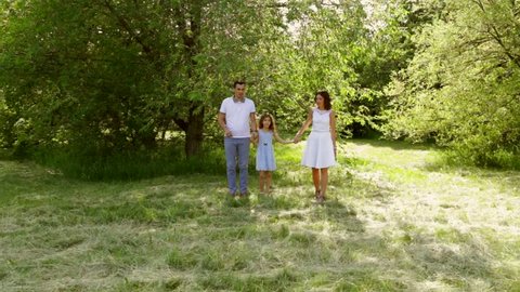Happy family running in a gorgeous picturesque park while holding hands with eachother