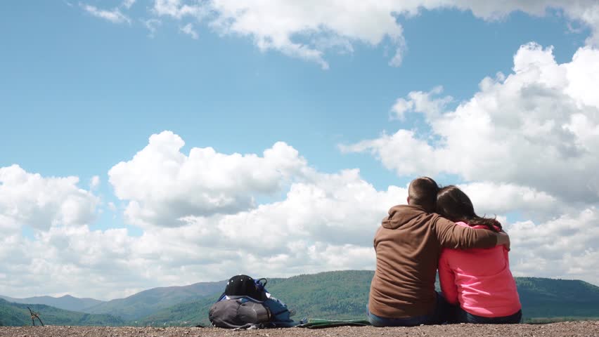 Young attractive tourist couple hugging and kissing on background of amazing blue sky