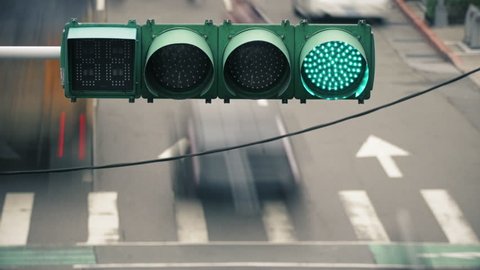 Time lapse of traffic lights over a busy rush hour road in Taipei, Taiwan. Many cars driving and people crossing. The traffic light features a timer for drivers and pedestrians. 4k resolution.