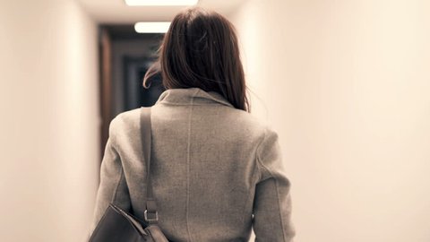 Young woman walking in hall in block of flats
