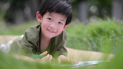 Cute Asian child drawing picture with crayon,outdoors
 Video stock