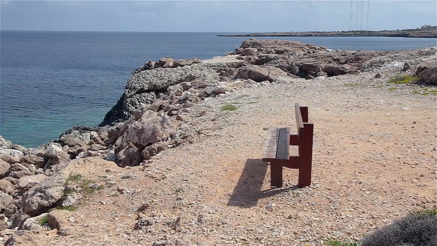 Lonely wooden bench on the rocky coast of the island of Cyprus. Cape Cavo Greco. Cyprus