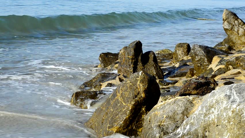 Small waves crashing on rocks on a tropical beach in Thailand.