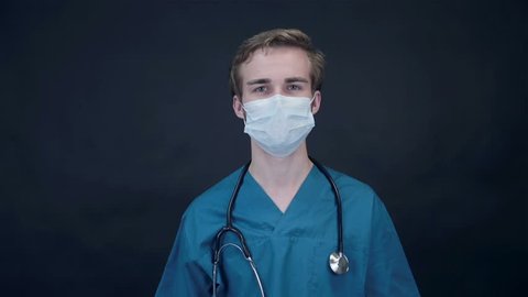 Smiling Doctor removes medical mask looking into screen. Packshot.