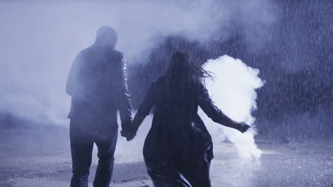 Couple running  in heavy rain accross the smoke. Shot on RED EPIC Cinema Camera in slow motion.