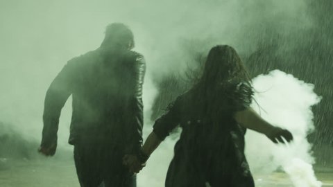 Couple running  in heavy rain accross the smoke. Shot on RED EPIC Cinema Camera in slow motion.