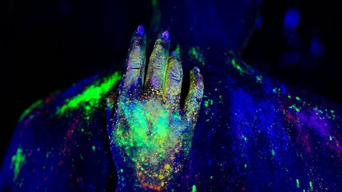 Woman's hand erotically slips on the man's on the back under ultraviolet light.