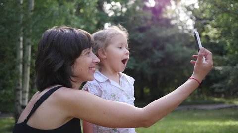 Happy family mother with child daughter taking selfie phone photo on nature