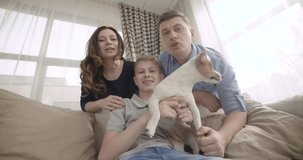 Happy family with cute dog talking to relatives using video chat on laptop at home. Point of view of the computer screen. 4K