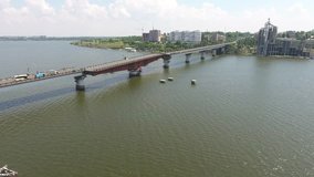 Aerial video, lift up of bridge on river against the background of city