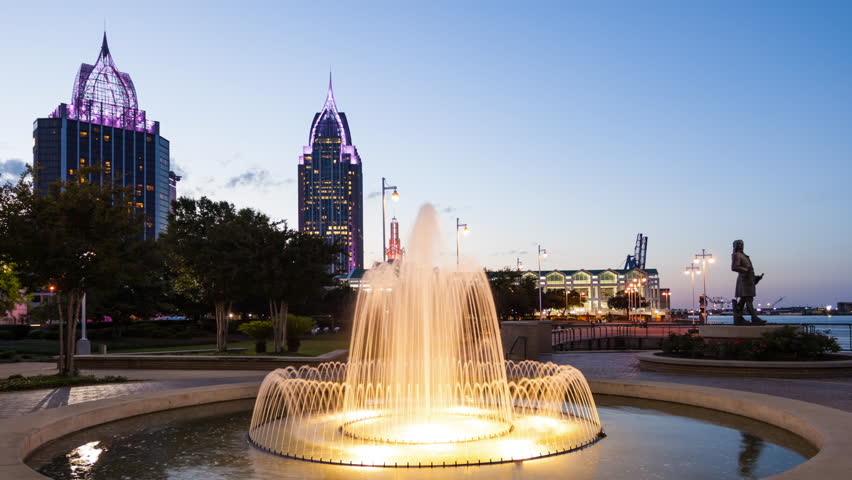 Downtown Mobile, Alabama skyline and water fountain as night falls in Cooper Riverside Park, timelapse