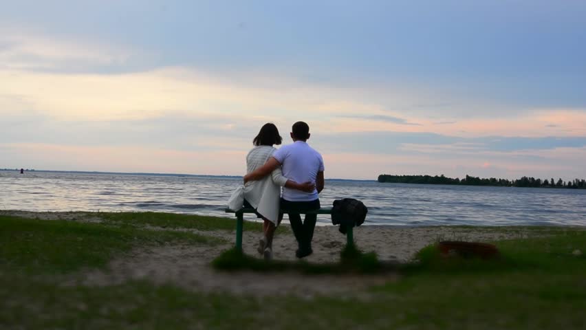 In Love and happy couple sitting on a bench by the river.