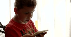 Close up of Kid Touching Screen of Tablet While Playing Video Games Sitting in the Chair