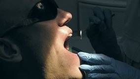 Man gets dental medical examination and treatment at the dentist clinic office. Odontic and mouth health is important part of modern human life that dentistry help with. 4K UHD video footage.