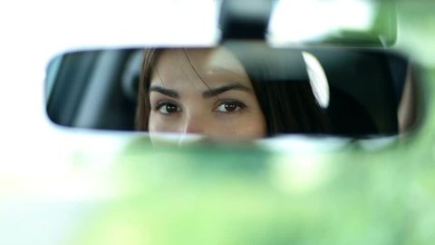 Young beautiful woman looking in rear view mirror