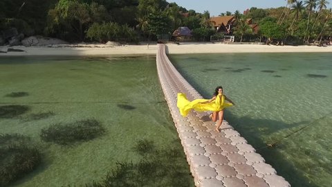 Woman in flying yellow dress on pontoon bridge
