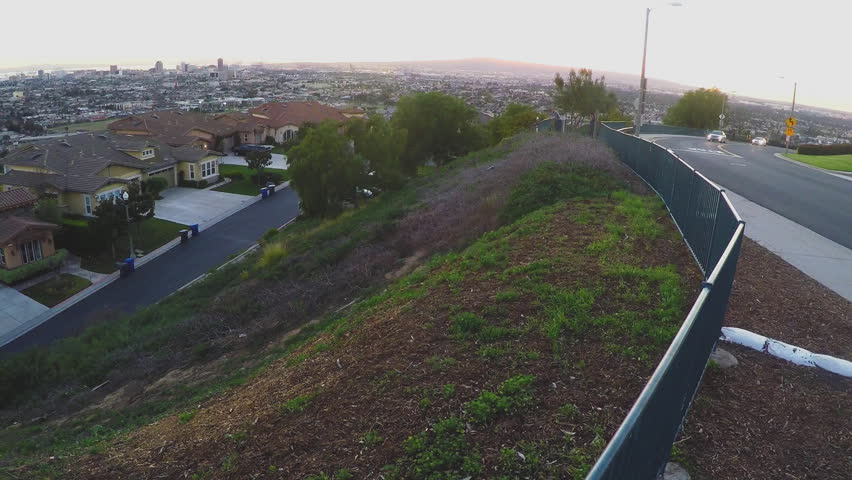 A long pan shot of Long Beach California from Signal Hill. The shot captures a suburban street neighborhood in the foreground and the city of Long Beach stretching to the ocean in background.