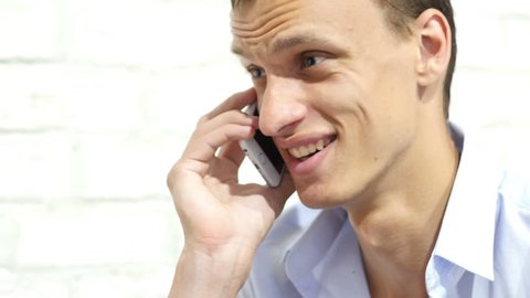Close up of young smiling businessman talking on smartphone