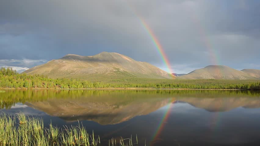 double rainbow over lake and mountains
