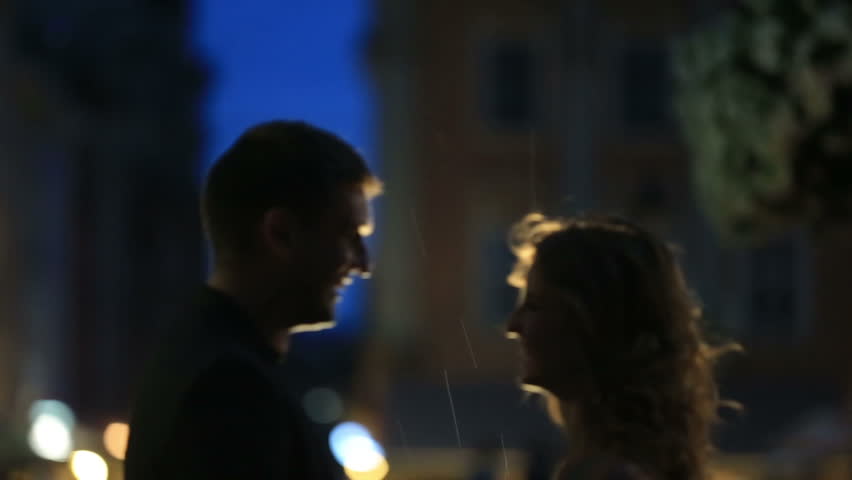 Loving couple talking on rain at the evening street of european city