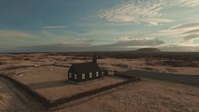 Drone footage of black church amidst landscape by sea at Budir
