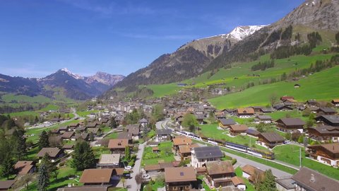 4K Golden Pass Train Switzerland aerial shot / Train arriving at Chateau-d'Oex in the Swiss Alps - Gruyere area