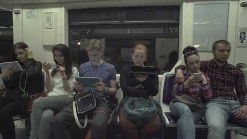 Young people reading news online, using app, texting on gadgetsin metro train