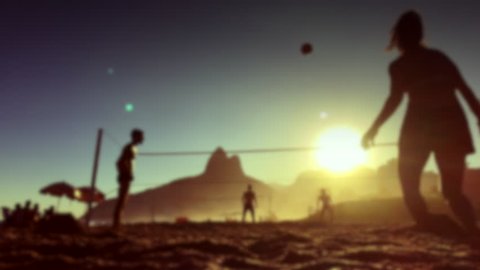 Defocus silhouettes playing Brazilian beach futevolei (footvolley), a sport combining football (soccer) and volleyball, at sunset on Ipanema Beach, Rio de Janeiro, Brazil