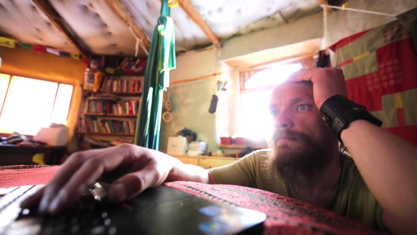 Man - settler of the Chachzaevka Ecovillage - is using his laptop. Altai mountains, Siberia, Russia. From 2011 people here explore alternative energy, green building, natural farming