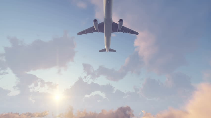 Passenger airplane flying overhead high in the sky above cumulus clouds at sunset. Realistic 3D animation rendered in 4K, ultra high definition.