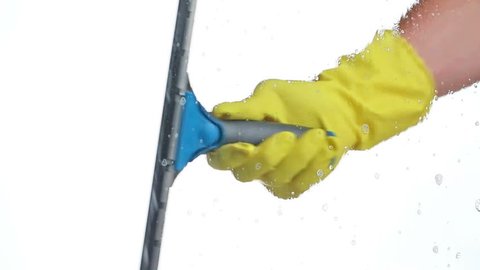 Man with rubber glove wipes cleaning detergent with large squeegee from window - housekeeping or cleaning industry concept