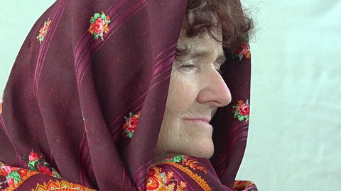 side portrait of a Caucasian old woman dressing an headscarf