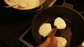 A cook flips over the fritters in the frying pan