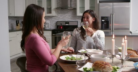 Female gay couple make a toast at dinner in their kitchen, shot on R3D