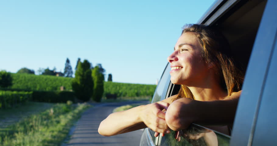 On a sunny day a beautiful woman puts the traveling head out the car window to admire the view and breathe pure air along with his friends that comes in her happy thoughts | Shutterstock HD Video #17917663
