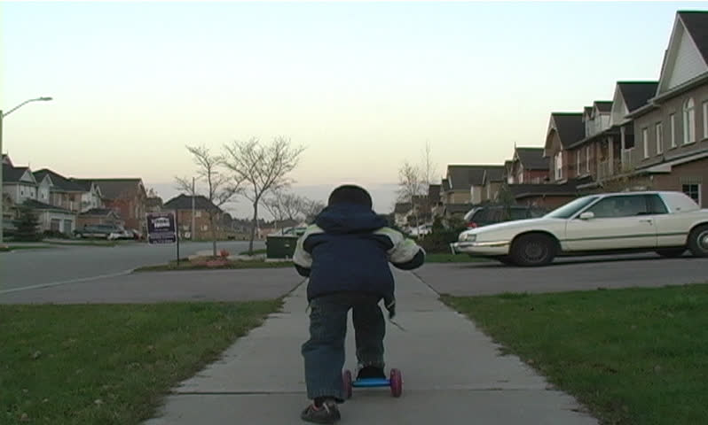 Boy riding a scooter on the sidewalk