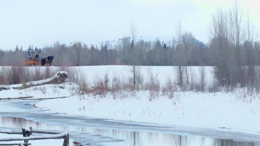 Horses pull a sled with passengers through the snow in Jackson Hole 